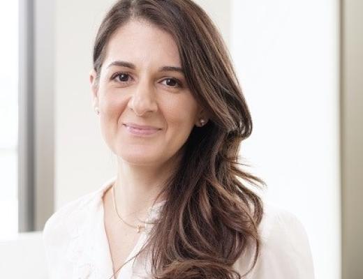A headshot of Professor Christina Messiou. She has long, dark curled hair and is wearing a white blouse with a golden necklance
