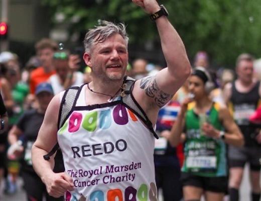 RMCC runner smiling with clenched fist in the air to supporters. 